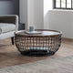 Round wooden coffee table with metal wire base in a modern living room.