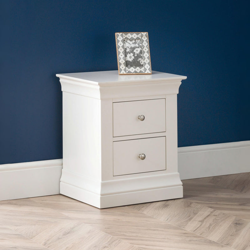 White nightstand with two drawers against a blue wall