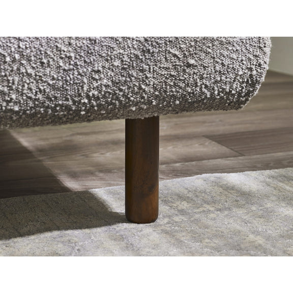 Close-up of a textured sofa corner with a wooden leg on a wooden floor.