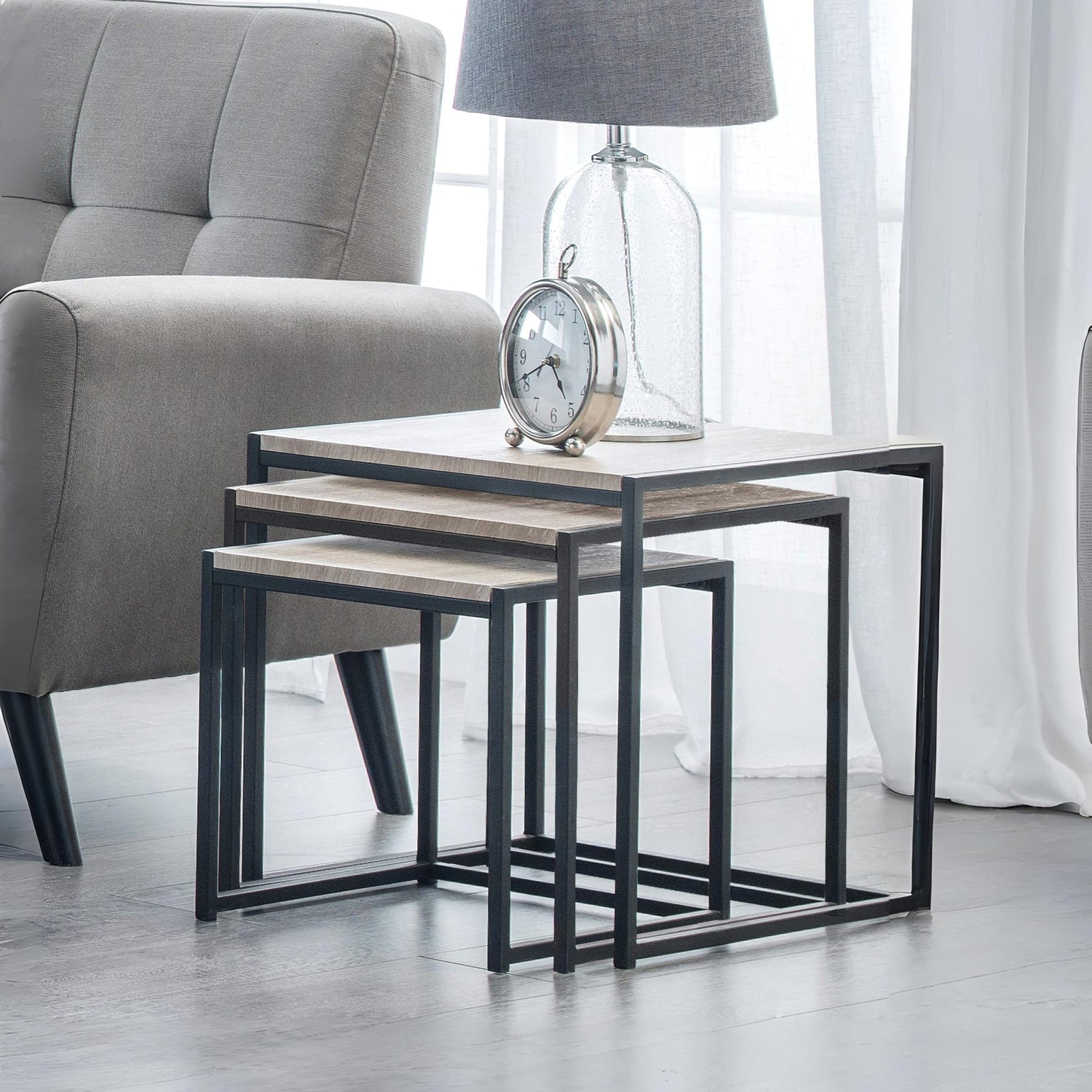 Set of three nesting tables with a clock and lamp in a living room setting.