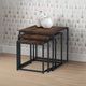 Set of three nesting tables with wooden tops and black metal frames against a patterned wall.