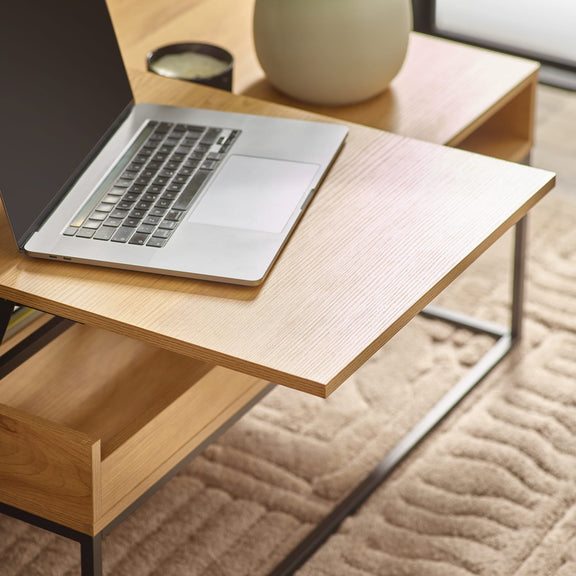 Laptop on a wooden desk with a vase in the background