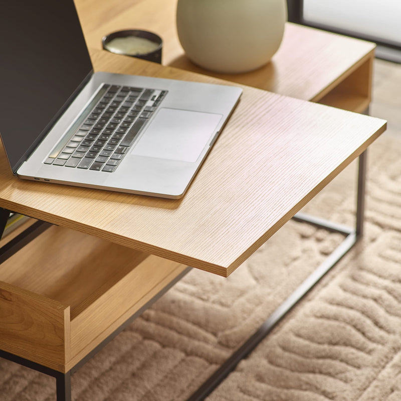 Laptop on a wooden desk with a vase in the background