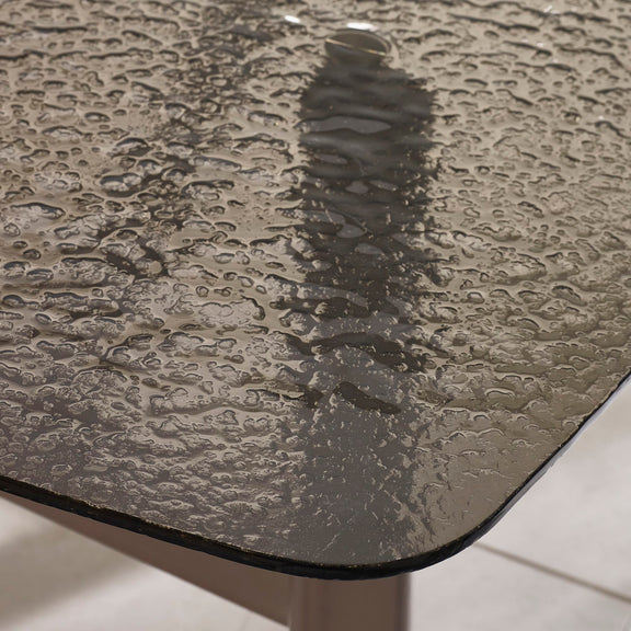 Textured glass surface with water droplets on a light background