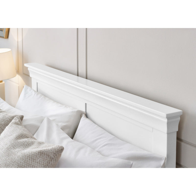 White wooden headboard with pillows on a bed in a bedroom setting