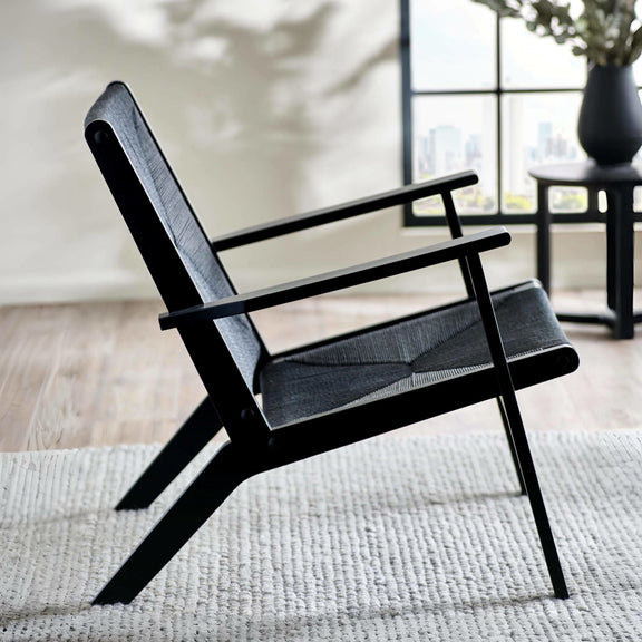 Black armchair with gray cushion on a light wooden floor