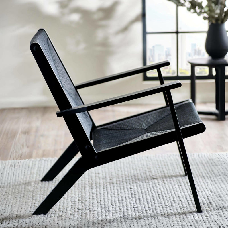 Black armchair with gray cushion on a light wooden floor