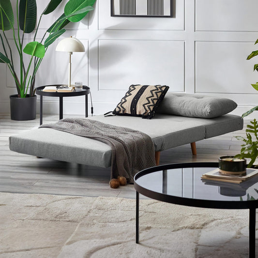 Gray sofa bed in a modern living room with a coffee table and decorative items.
