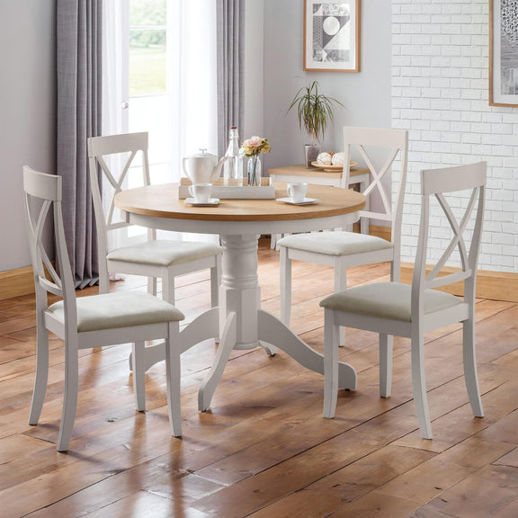 Dining room with a round wooden table and four matching chairs on a wooden floor.