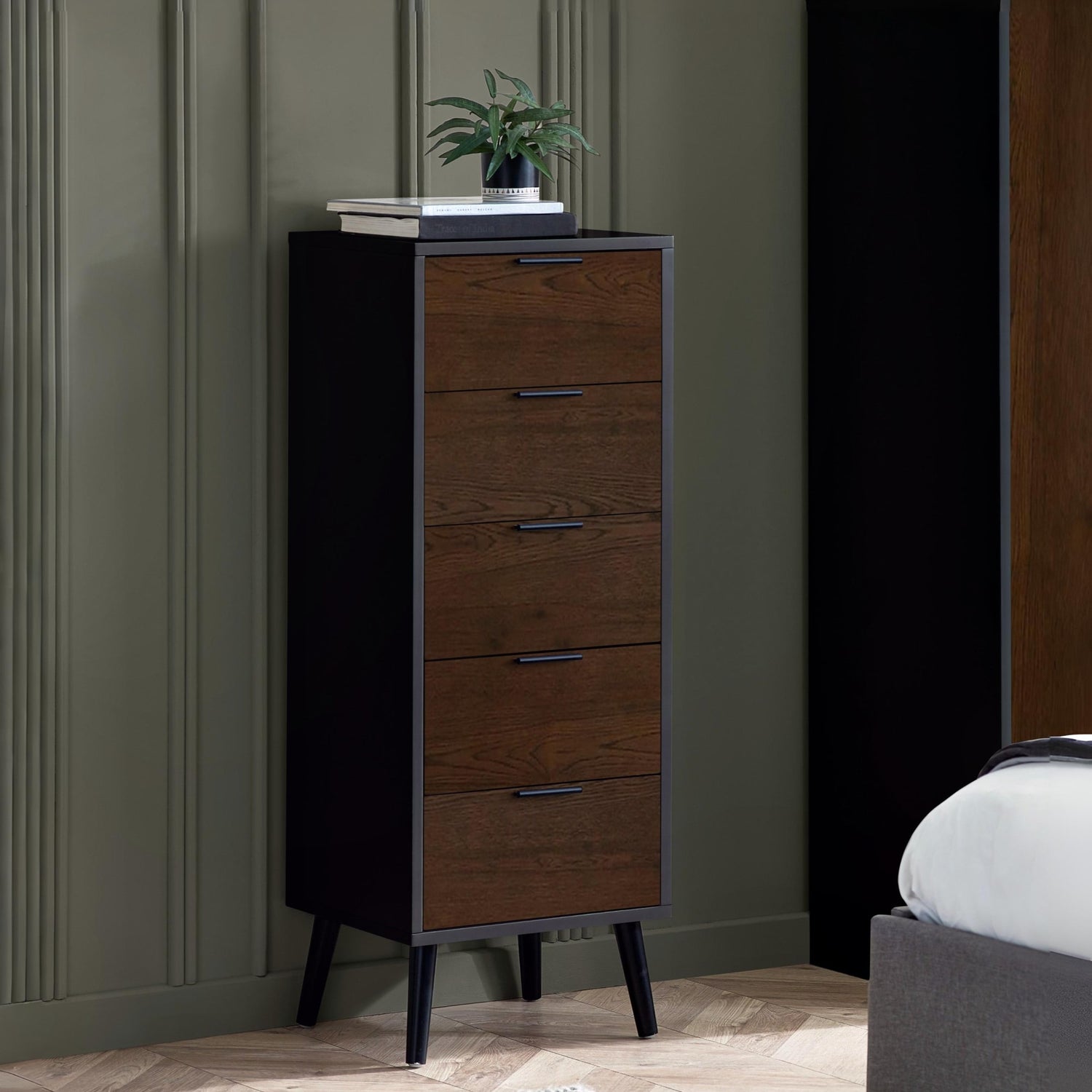 Wooden dresser with four drawers against a gray wall in a room setting.