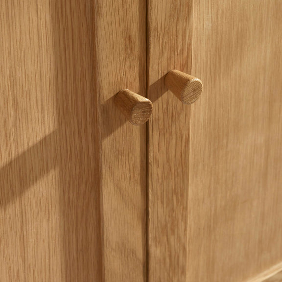Close-up of a wooden cabinet with two handles on a wooden surface.