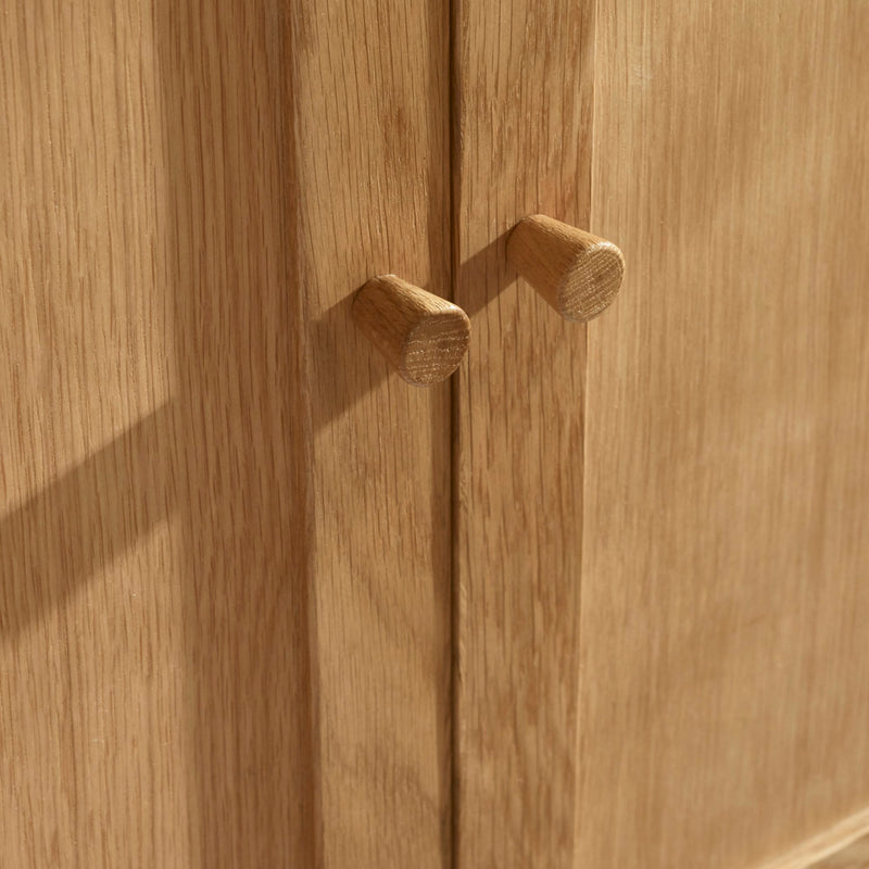 Close-up of a wooden cabinet with two handles on a wooden surface.