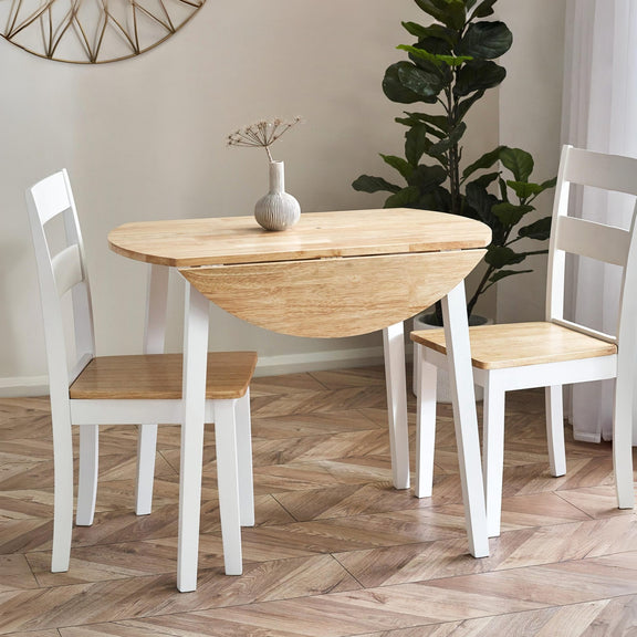 Wooden dining table with white legs and chairs on a wooden floor.