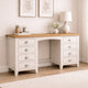 White desk with wooden top in a room with framed artwork and a lamp.