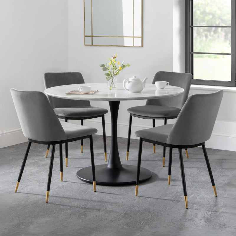 Dining room setup with a round table and gray chairs in a modern interior.