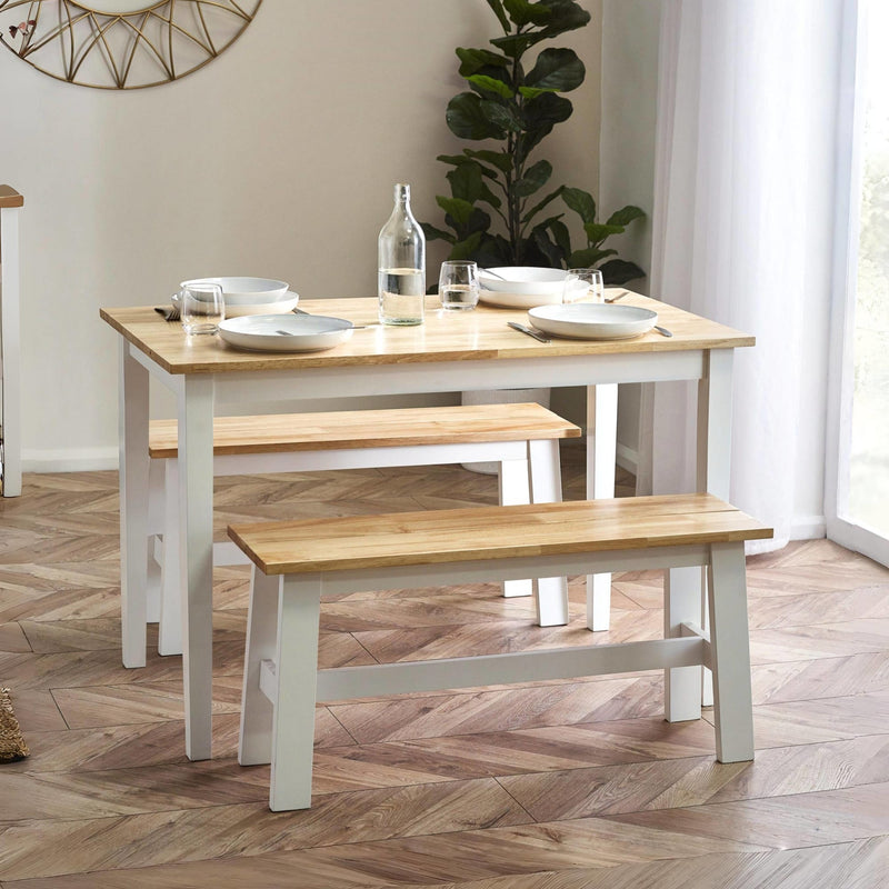Dining table with benches in a room with a plant and window.