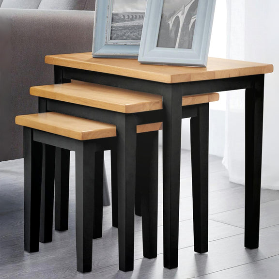 Set of three nesting tables with wooden tops and black legs on a light-colored floor.