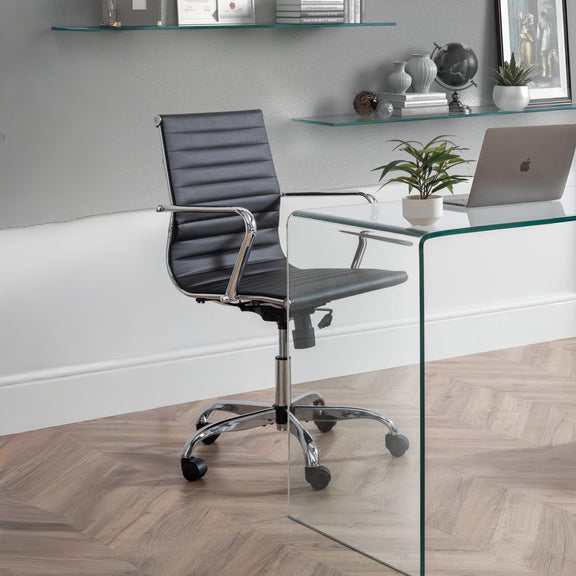 Modern office chair in front of a glass desk with a laptop and decor items.