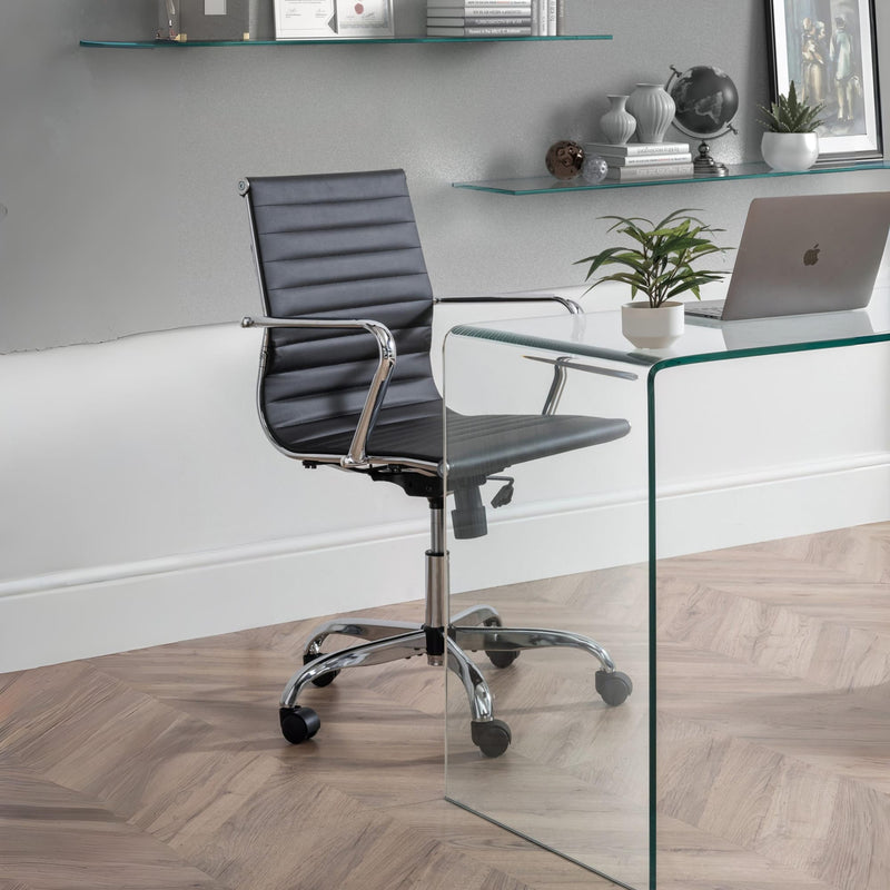 Modern office chair in front of a glass desk with a laptop and decor items.