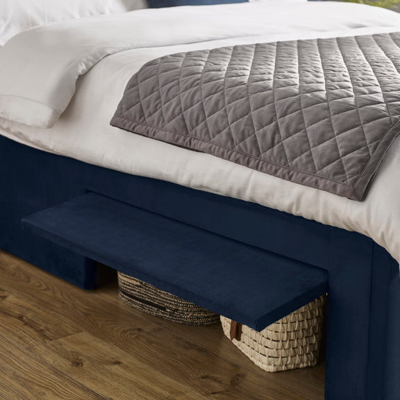 Navy bed rail attached to a bed with white bedding and a gray quilt.