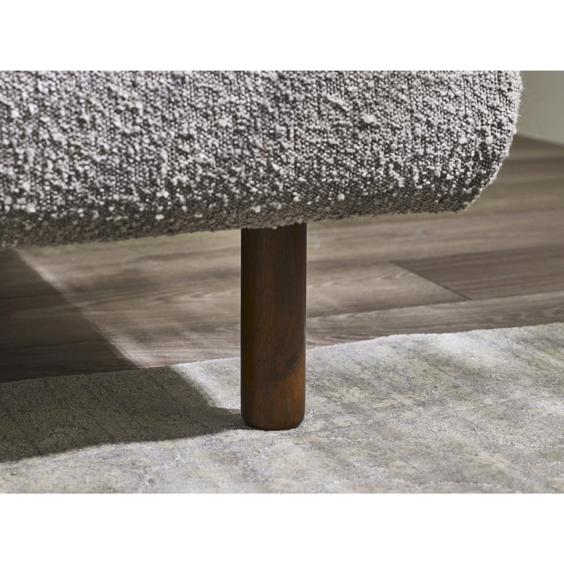 Close-up of a textured sofa corner with a wooden leg on a wooden floor.