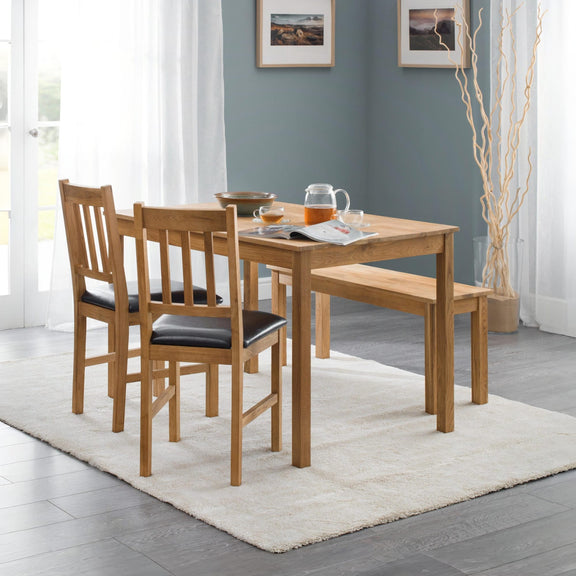 Wooden dining set with table and chairs in a room with light blue walls and white curtains.