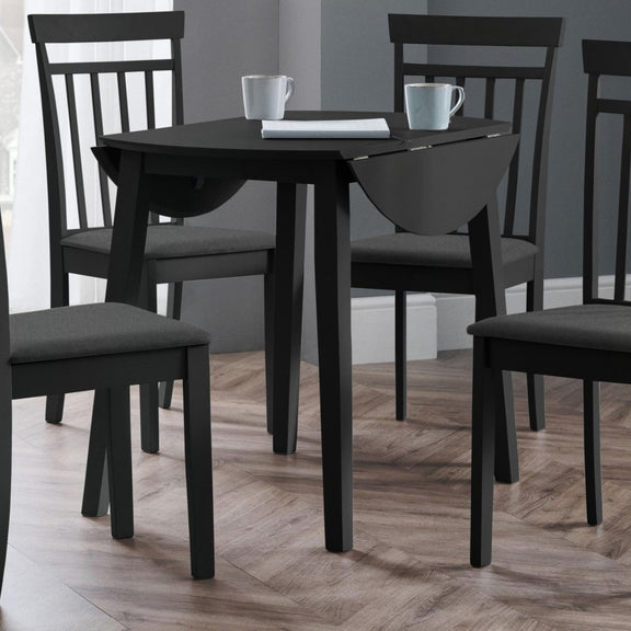 Black dining table with four chairs on a wooden floor.