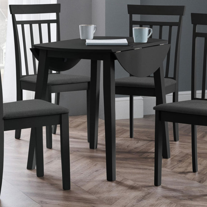 Black dining table with four chairs on a wooden floor.