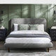 Gray upholstered bed with white bedding in a bedroom setting with green walls.