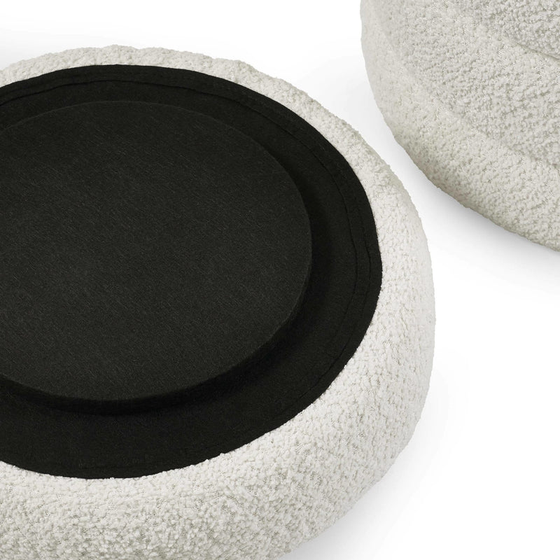 Round textured ottoman with a black cushion on a white background