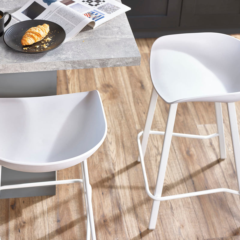 White chairs around a table with a croissant and newspaper on a wooden floor.