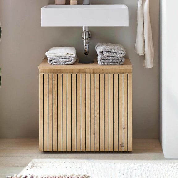 Bathroom with wooden cabinet under a sink, featuring folded towels.