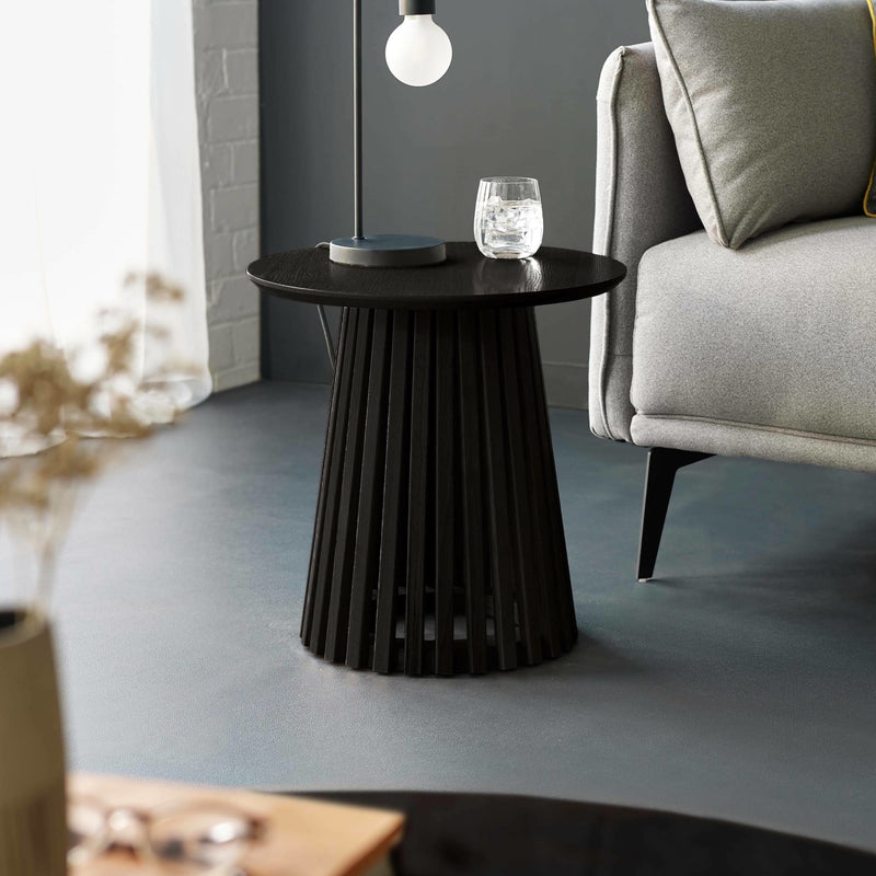 Wooden side table with a lamp and glass in a living room setting