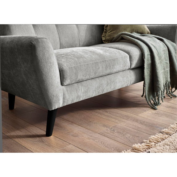 Gray sofa with a green blanket on a wooden floor