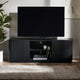 Black TV stand with a television on top in a room with a plant and rug.
