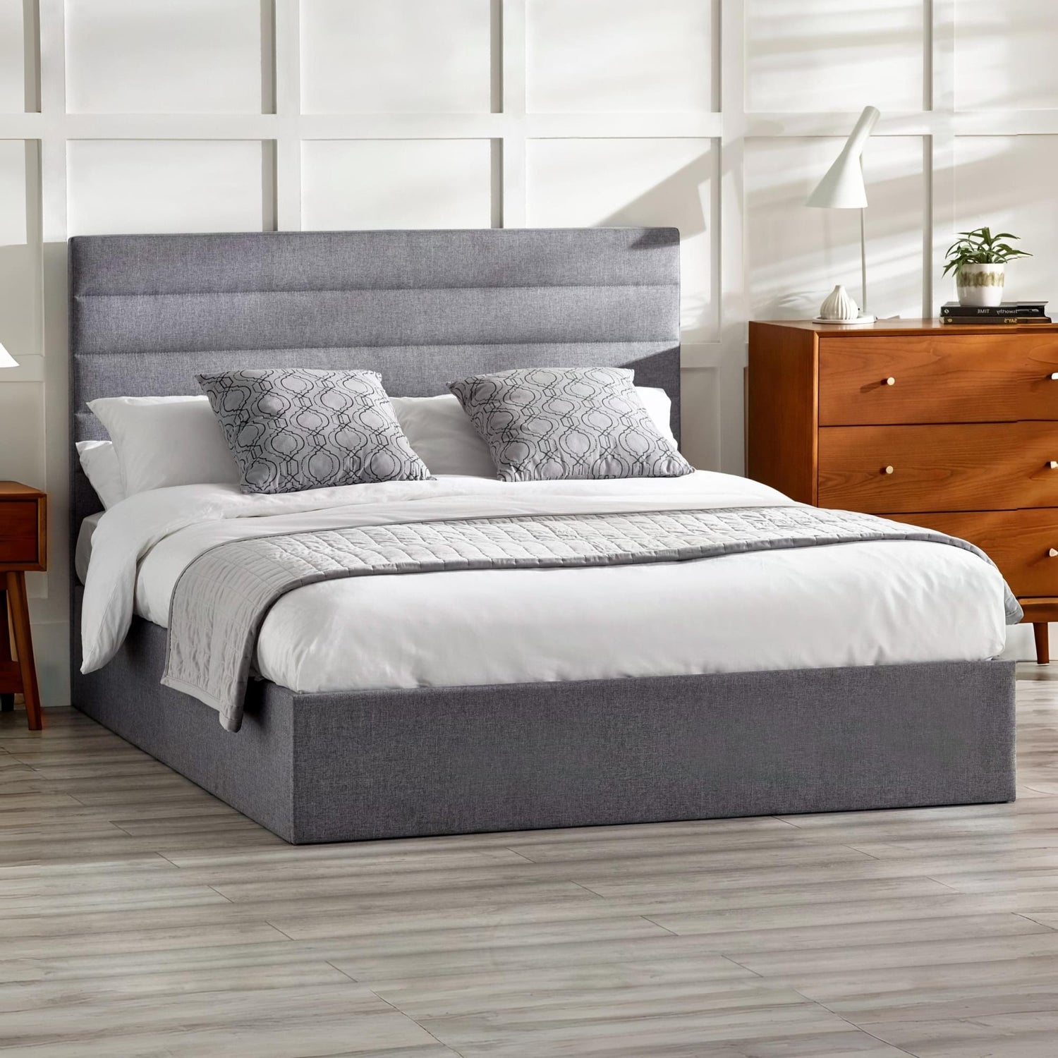 Gray upholstered bed with white bedding in a bedroom setting.