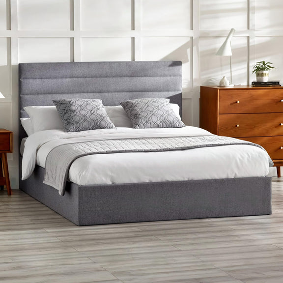 Gray upholstered bed with white bedding in a bedroom setting.