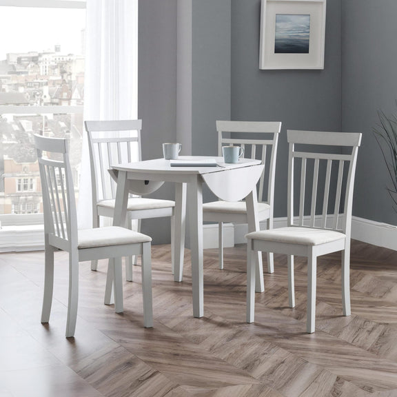 White dining set with four chairs around a table in a room with a large window and gray walls.