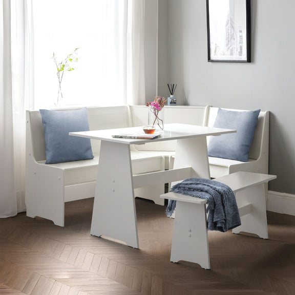 White dining set with bench and table in a room with light gray walls and wooden flooring.
