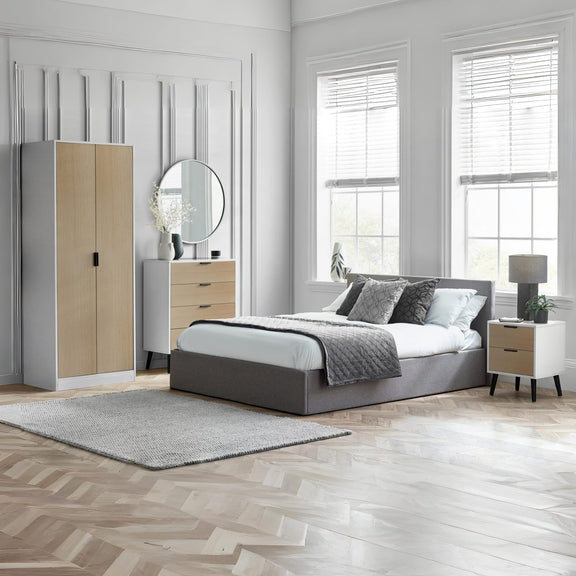 Modern bedroom with gray bed, wooden wardrobe, and side tables.