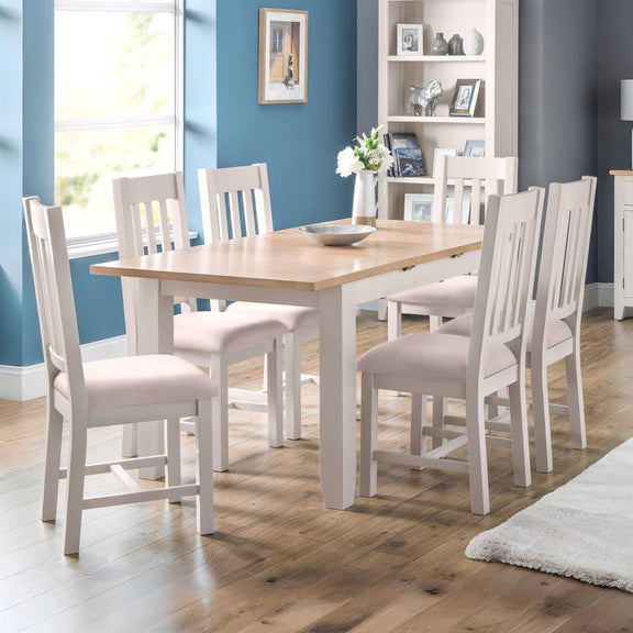 Dining room with wooden table and white chairs against a blue wall.