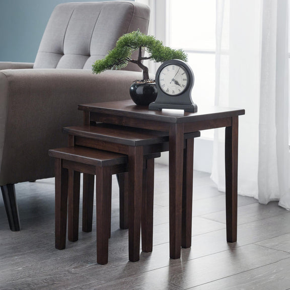 Set of four dark wood nesting tables in a living room setting with a chair and decorative items.