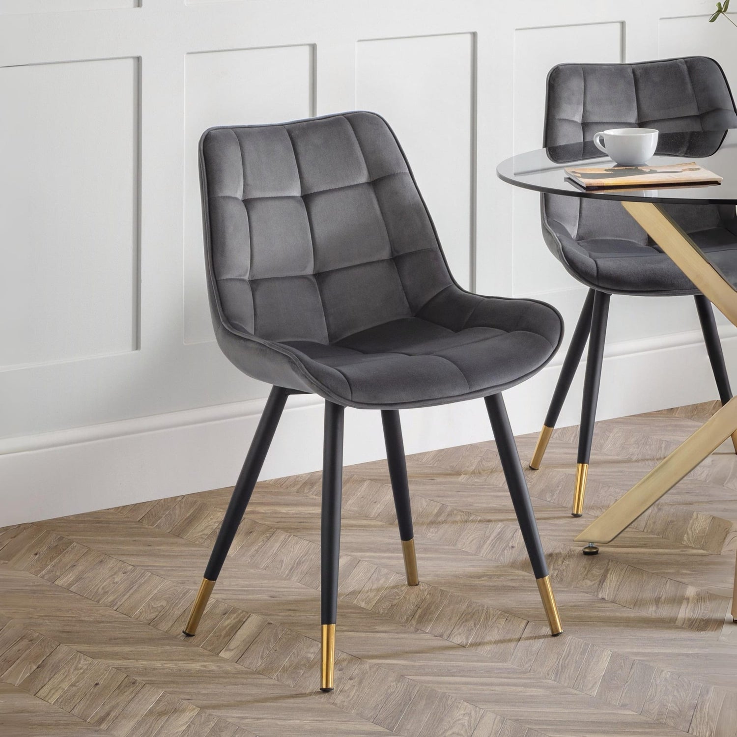 Gray upholstered chair with gold feet on a wooden floor