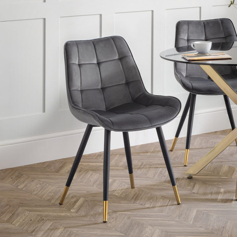 Gray upholstered chair with gold feet on a wooden floor