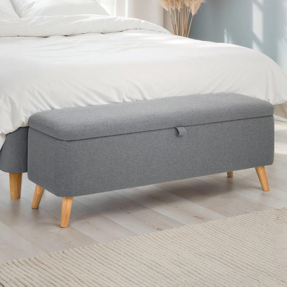 Gray storage bench with wooden legs in a bedroom setting
