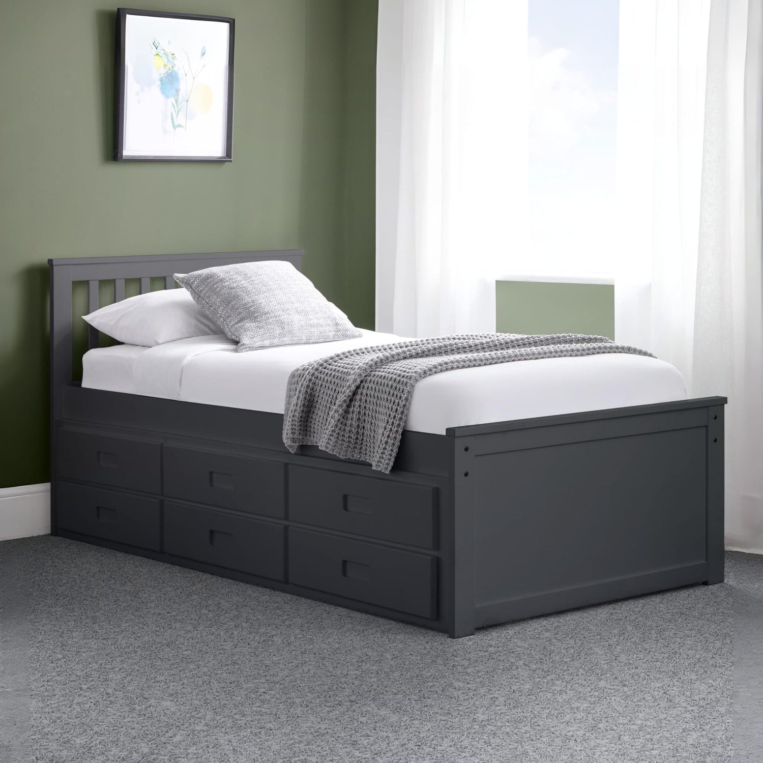 Black bed frame with storage drawers in a room with green walls and white curtains.