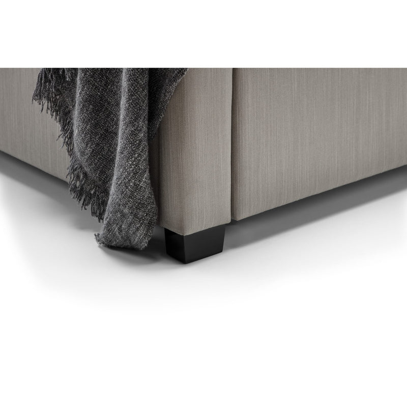 Gray upholstered bed with a textured blanket on a white background