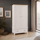 White wardrobe with wooden top in a room with dark walls, framed pictures, and a window.