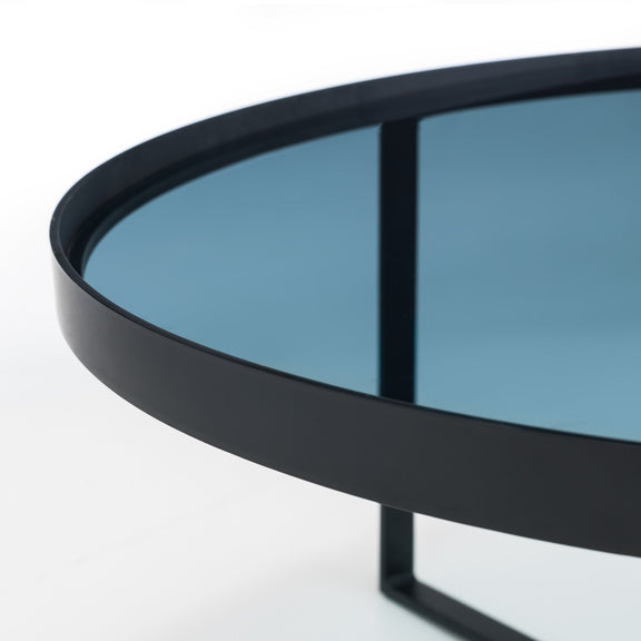 Round black metal table with a reflective surface on a white background