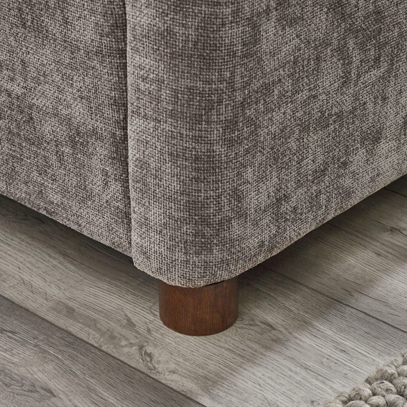 Brown textured fabric sofa with wooden legs on a wooden floor